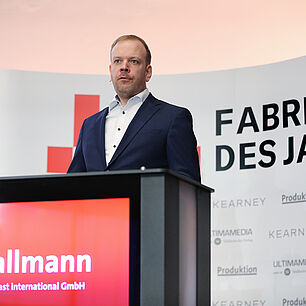FABRIK DES JAHRES - Tobias Hallmann auf der Bühne hinter dem Rednerpult und spricht zum Publikum